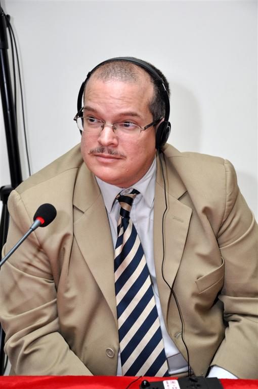 Fernando Báez speaking on a panel, wearing interpretation headphones